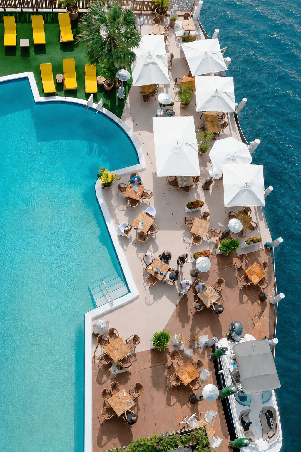 Vue aérienne d’un complexe hôtelier avec une piscine, des chaises longues et des espaces de détente en plein air.