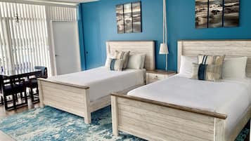 Quarto com duas camas, uma mesa de jantar e uma parede azul decorativa.