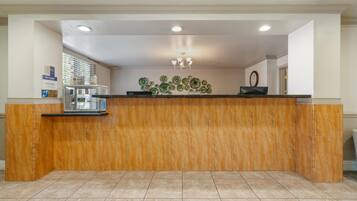 A reception area with a marble counter, a chandelier, and a wall-mounted display.