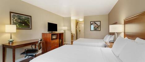 Habitación de hotel con dos camas, un escritorio con silla, televisión y armario.