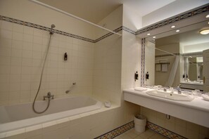 Un baño con bañera, dos lavamanos, un espejo y ducha.
