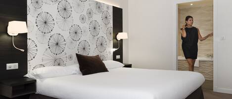 Una habitación de hotel moderna con una cama grande, dos lámparas de noche y una pared decorativa con un diseño de diente de león.