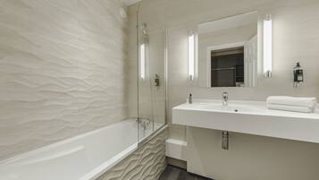 A modern bathroom with a freestanding bathtub, a large mirror, and a white vanity.