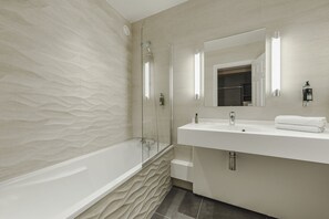 Une salle de bain moderne avec une baignoire sur pieds, un grand miroir et un meuble-lavabo blanc.