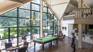 Una sala de billar con mesa de pool, sillas y una zona de bar.