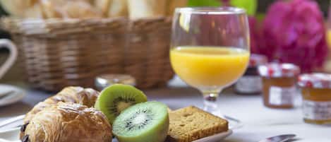 A breakfast setting with pastries, sliced kiwi, toast, and a glass of orange juice.