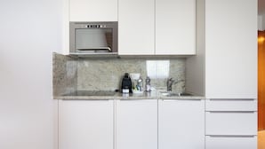 Cocina moderna con armarios blancos, horno empotrado, encimera de granito y pileta de acero inoxidable.