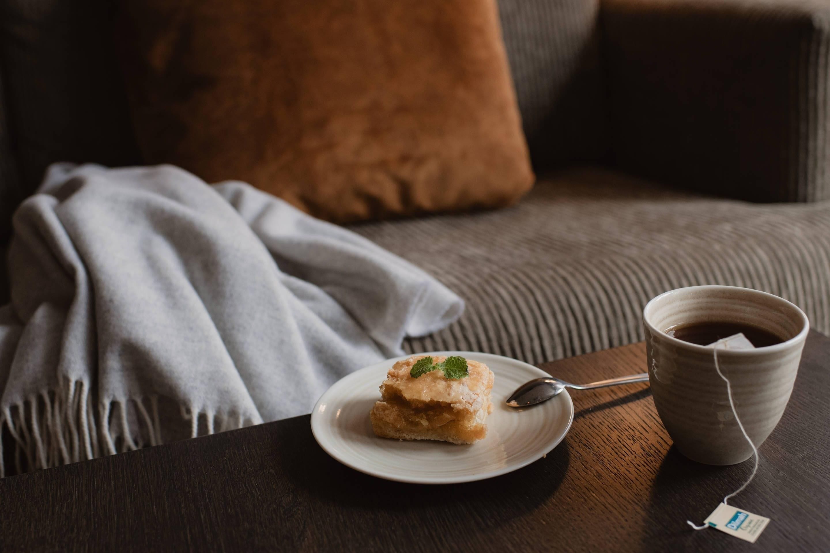 Un coin salon confortable avec une assiette de desserts et une tasse de thé posée sur une table.