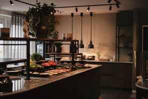 Una cocina moderna con una isla central que exhibe diferentes alimentos, lámparas colgantes y una planta en maceta.