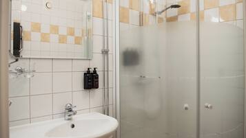 A bathroom with a sink, mirror, and shower.