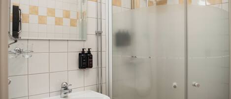 Baño con lavamanos, espejo y ducha.