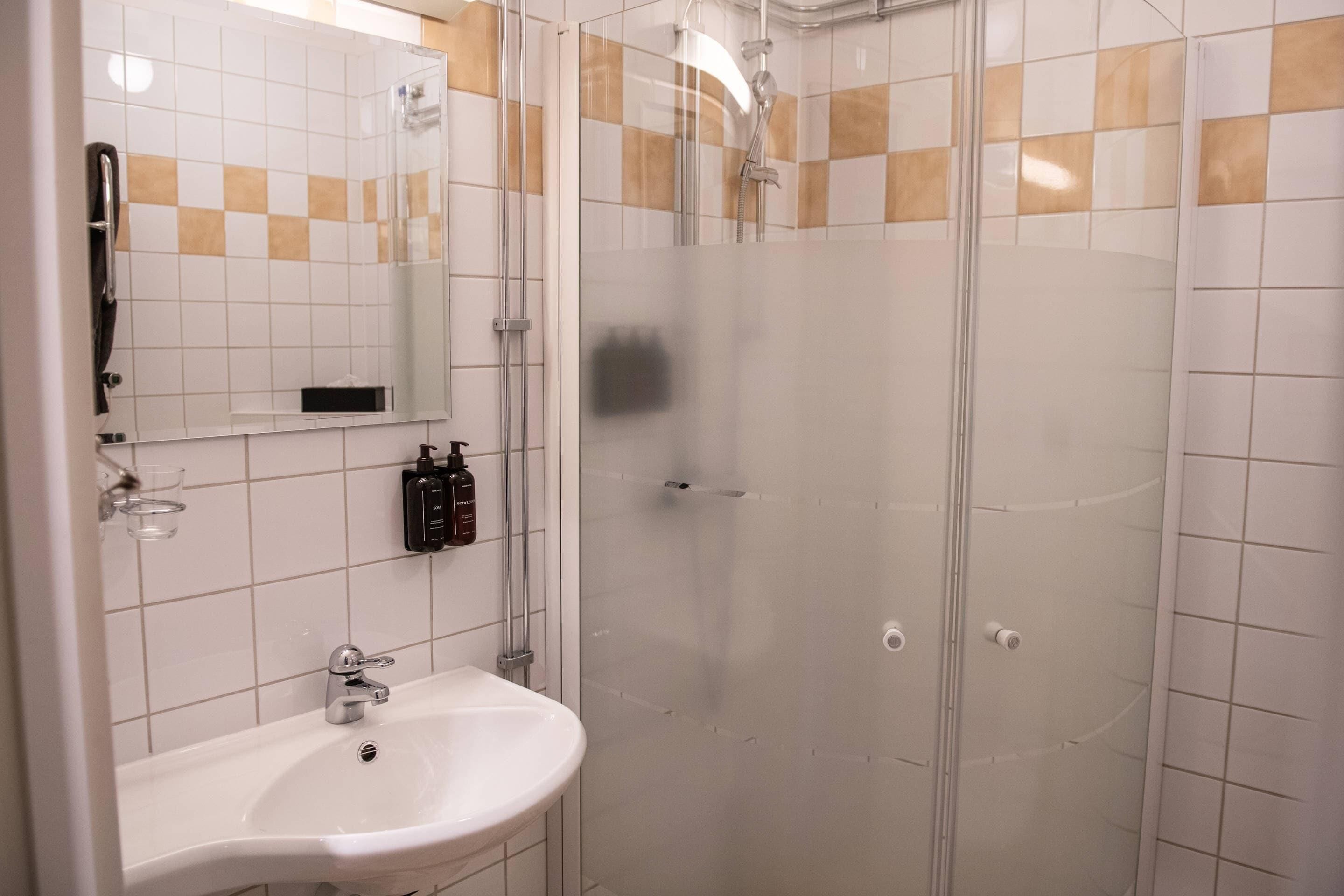 A bathroom with a white sink, a mirror, and a glass-enclosed shower.