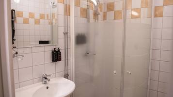 A bathroom with a white sink, a mirror, and a glass-enclosed shower.