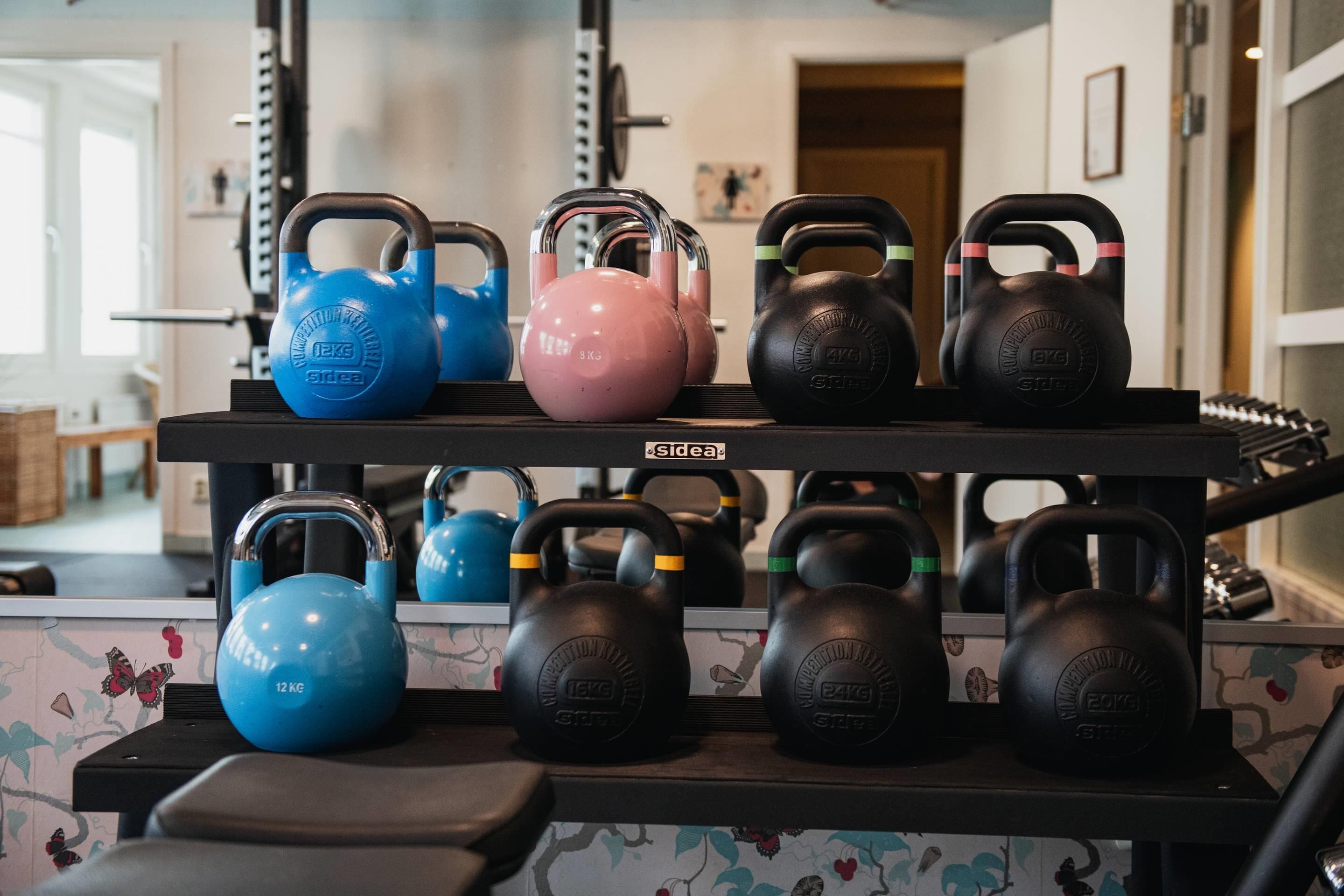 Un estante con mancuernas de kettlebell en varios colores y pesos.