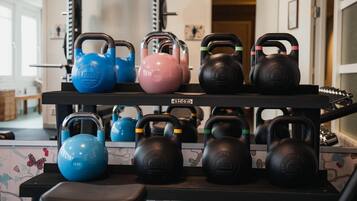 Un estante con mancuernas de kettlebell en varios colores y pesos.