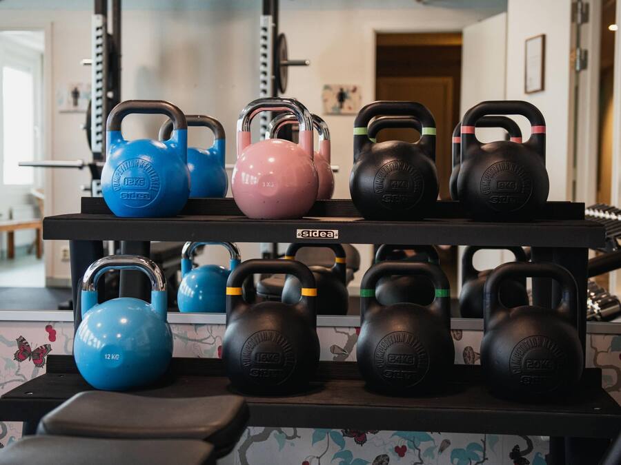 Un estante con mancuernas de kettlebell en varios colores y pesos.