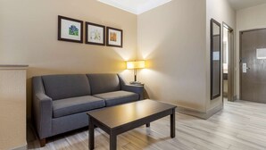 Una sala de estar moderna con un sofá gris, una mesa de centro de madera y una lámpara de pie. Hay tres cuadros en la pared.
