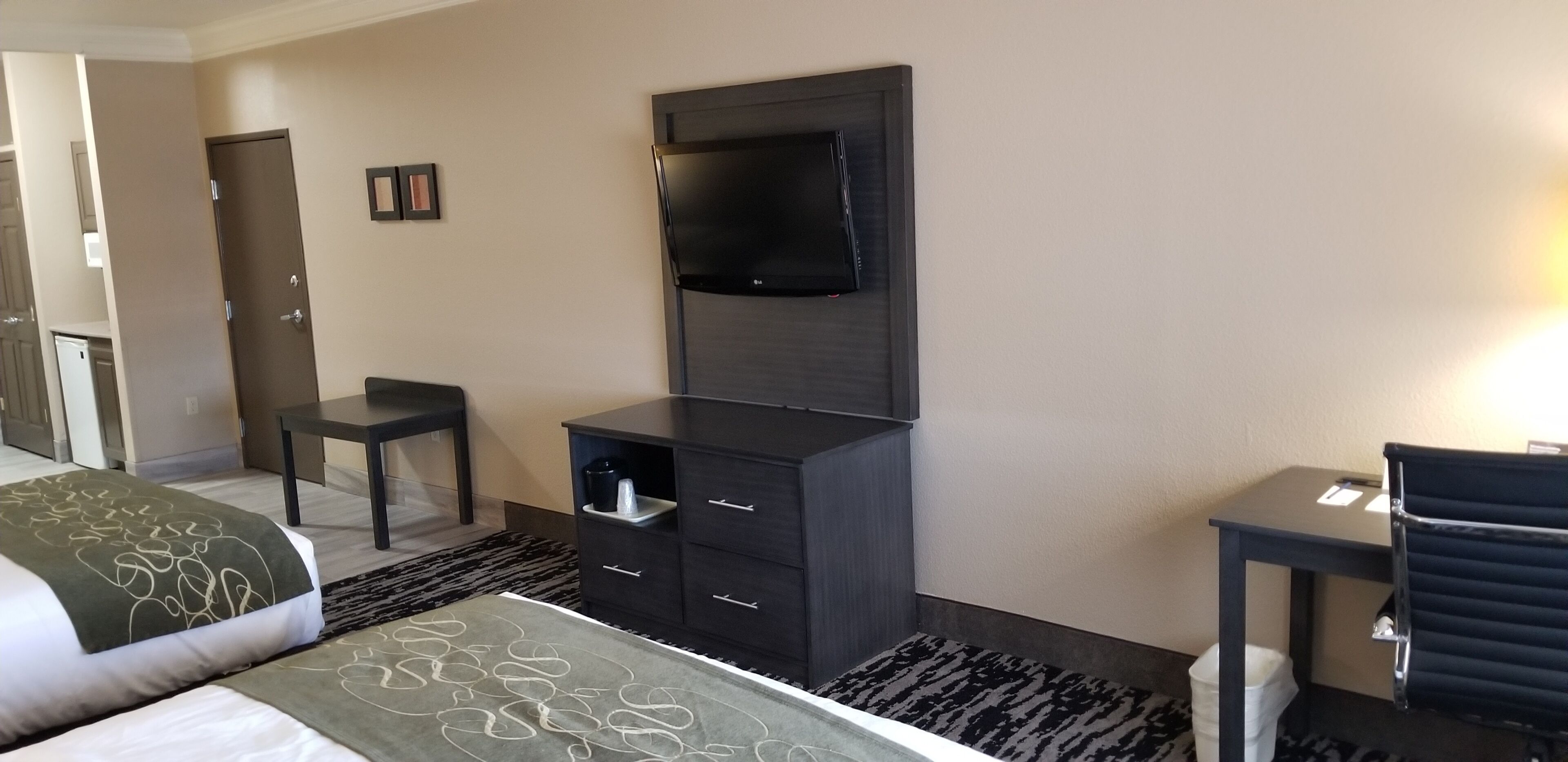 Une chambre d’hôtel comprenant un lit, un bureau, une chaise, une télévision et une armoire.
