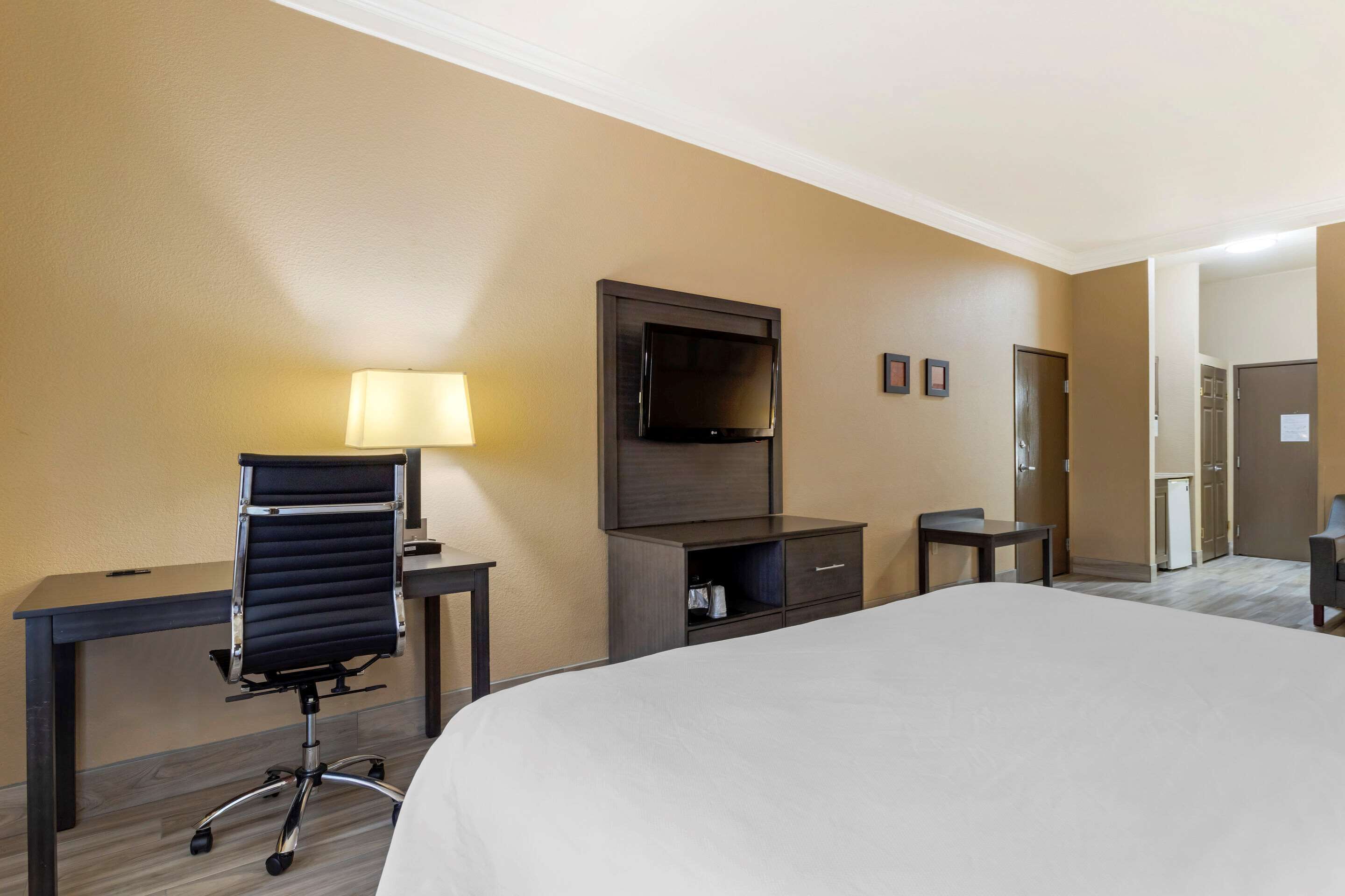 Une chambre d’hôtel avec un lit, un bureau, une chaise, une télévision et une lampe.
