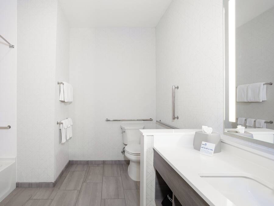 A modern bathroom with a toilet, a shower, a vanity with a mirror, and a towel rack.