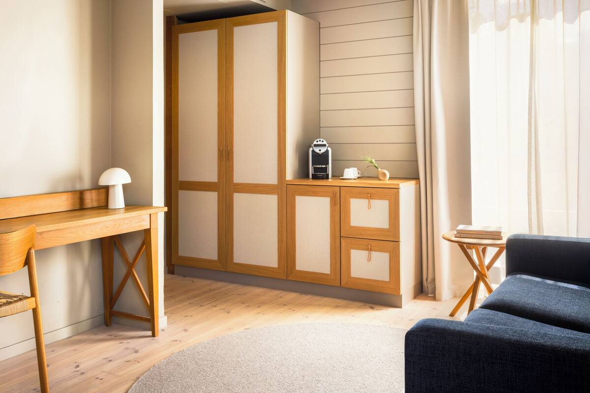 Une pièce avec un bureau en bois, un canapé bleu, une petite table sur laquelle se trouve un livre et un meuble.