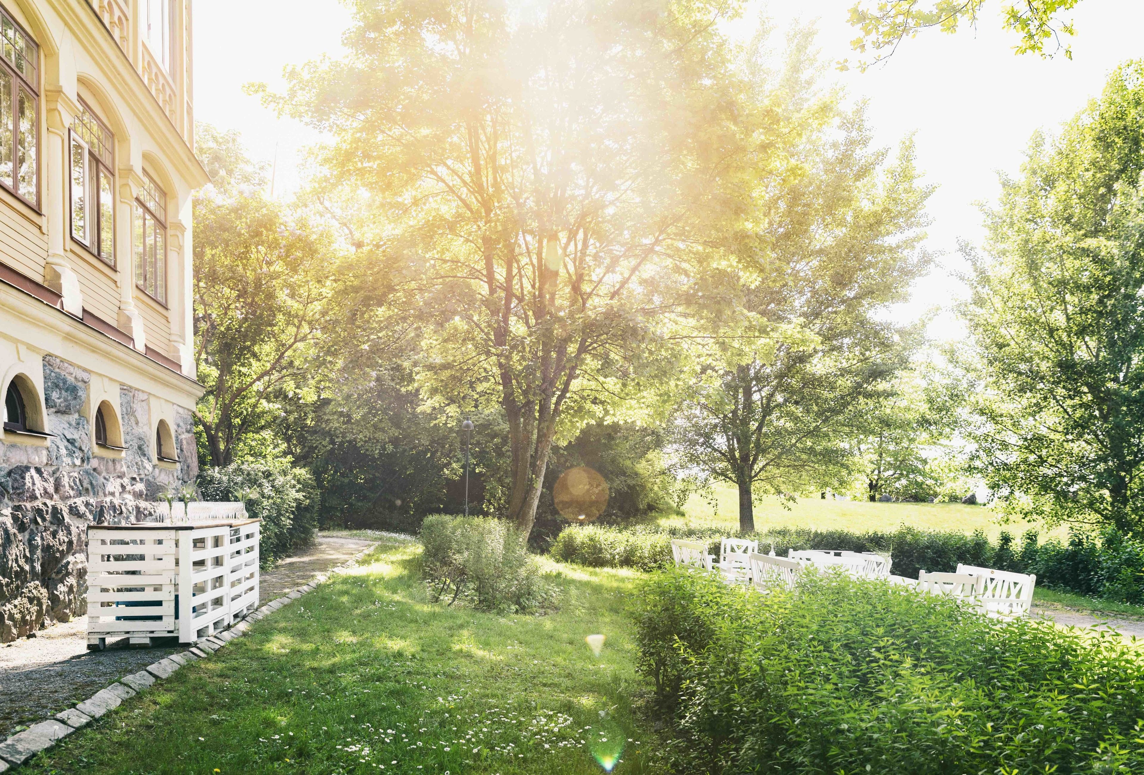 A courtyard with a building, trees, and a white fence.