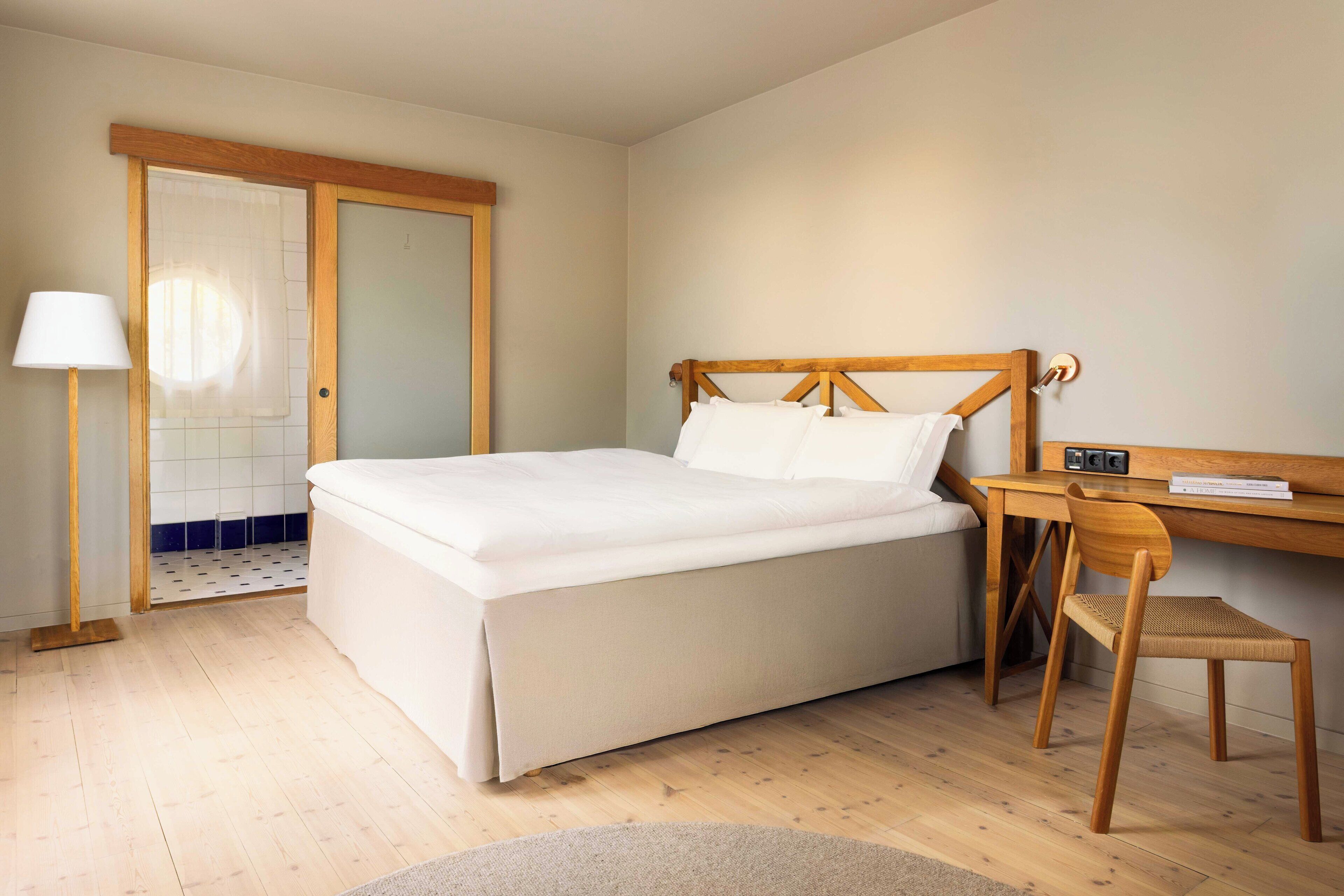 A neatly arranged bedroom with a bed, a desk, and a chair.