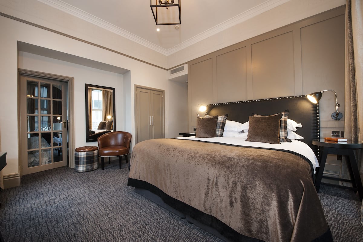Une chambre d’hôtel avec un grand lit, une chaise, une table de chevet et une armoire.