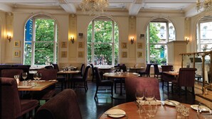 Un restaurante con varias mesas, sillas y una araña.