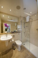 A modern bathroom with a glass shower enclosure, a white sink, and a toilet.