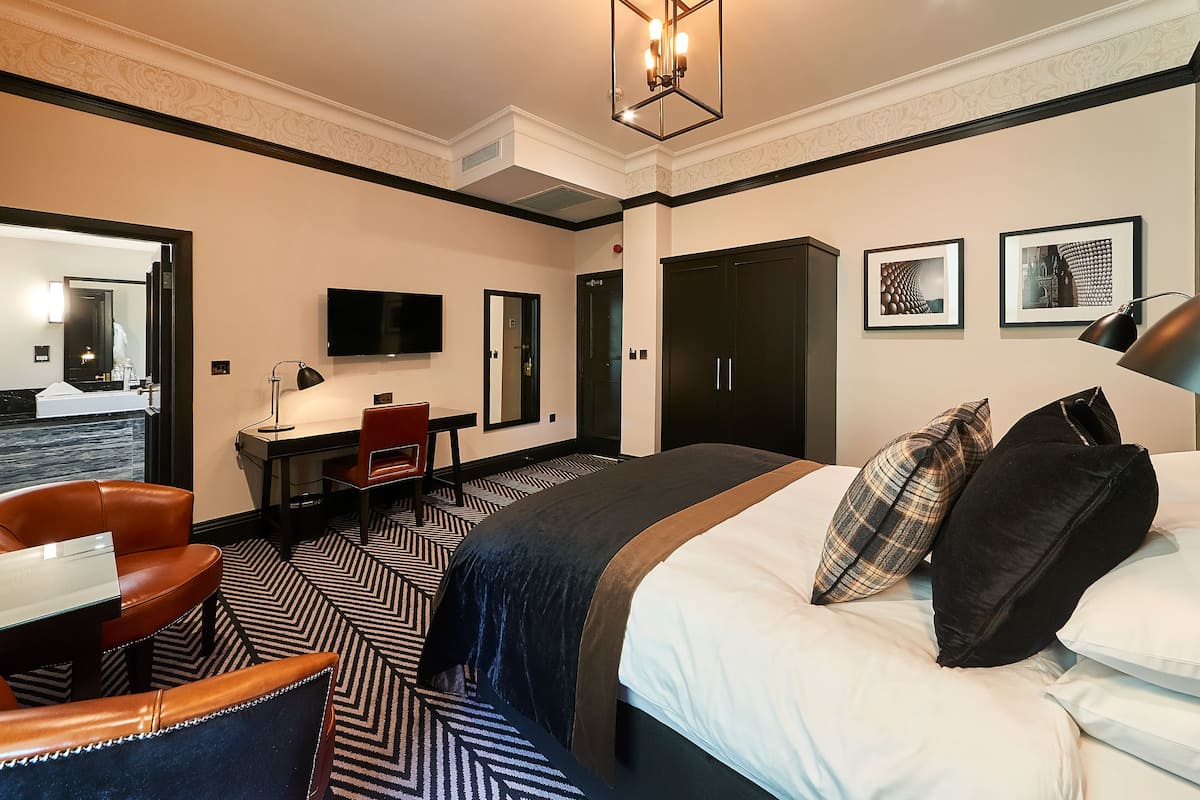 Une chambre d’hôtel comprenant un lit, un bureau, une chaise, une télévision et une armoire.