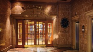 Entrada de hotel con puertas dobles, un letrero sobre la puerta y una zona de recepción visible a través de los cristales.