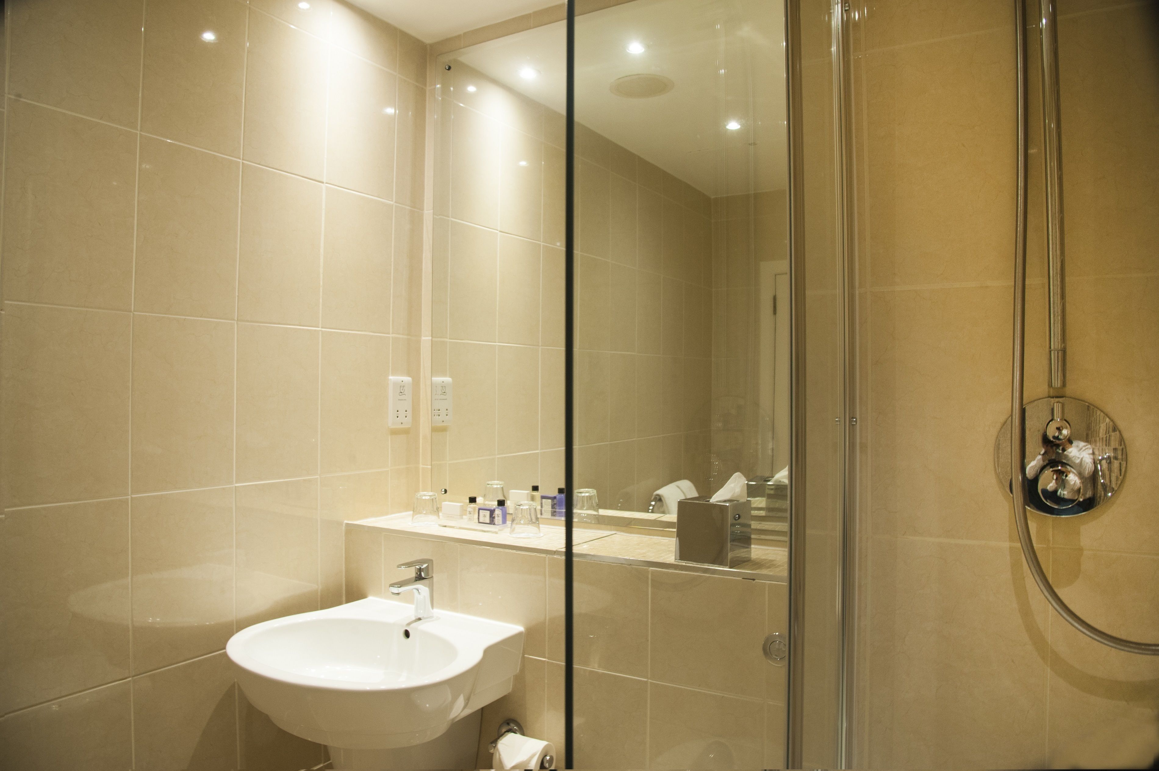 Un baño moderno con ducha acristalada, lavabo blanco y espejo.