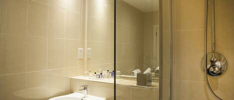 Un baño moderno con ducha acristalada, lavabo blanco y espejo.