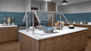 A modern kitchen with a central island, stainless steel appliances, and a blue-tiled backsplash.