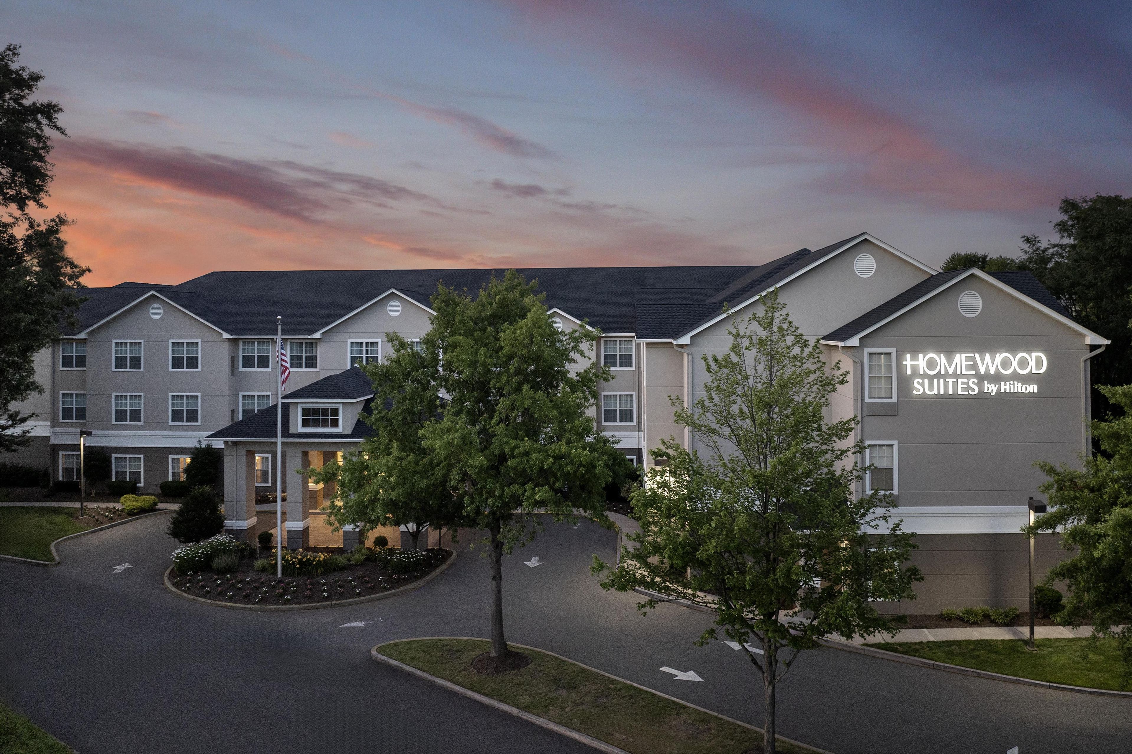 Um hotel com design moderno, exibindo uma placa chamativa para "HOMEWOOD SUITES by Hilton".