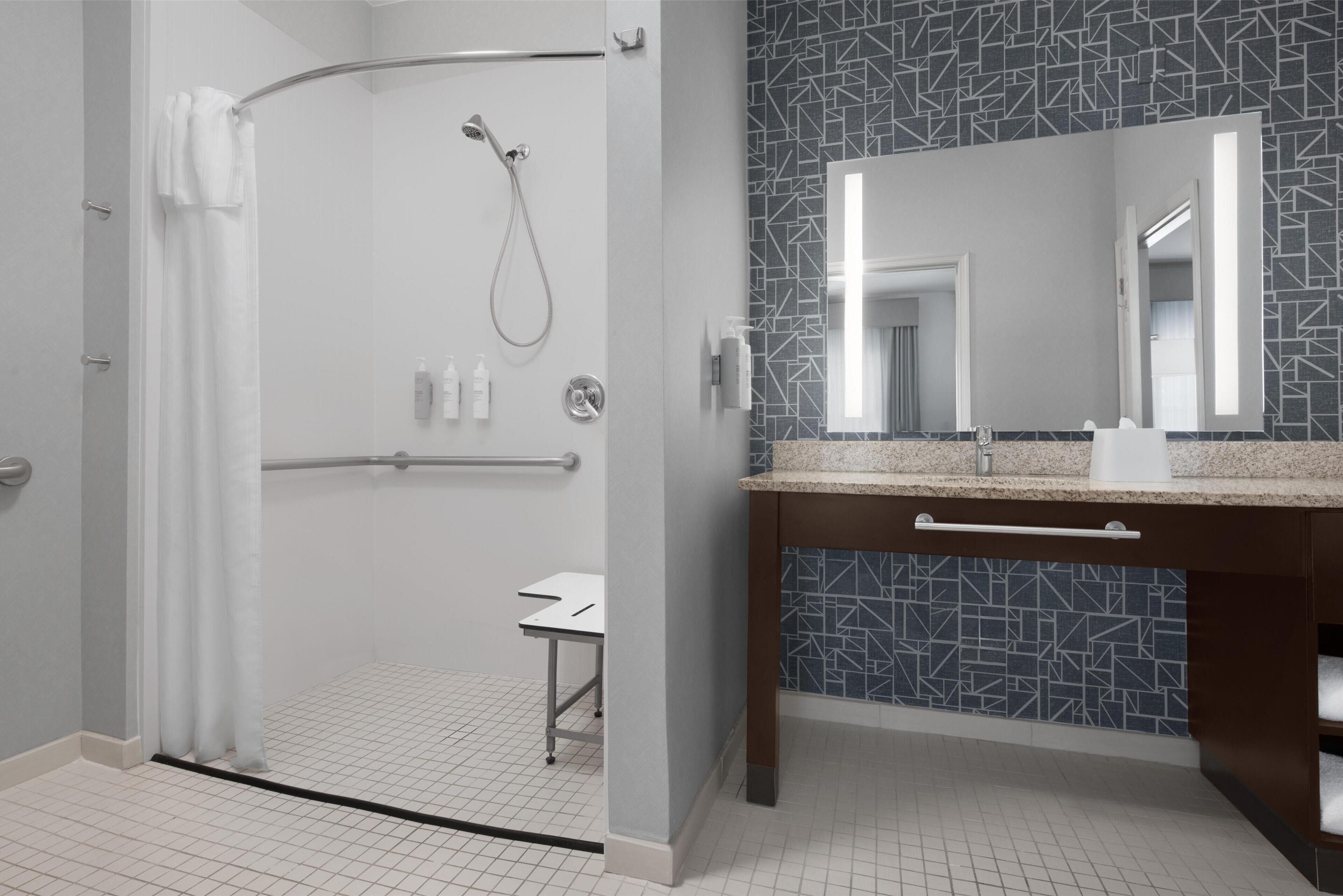 Une salle de bain moderne avec une douche, un meuble-lavabo avec un miroir et un pare-splash en carrelage.