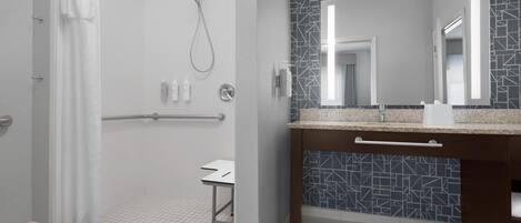 Une salle de bain moderne avec une douche, un meuble-lavabo avec un miroir et un pare-splash en carrelage.