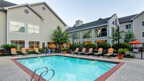 A swimming pool with lounge chairs and a building with large windows in the background. - Homewood Suites by Hilton Houston-Kingwood Parc-Airport Area (Kingwood)
