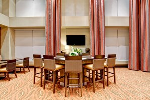 A conference room with a round table, chairs, a flat-screen TV, and a floral arrangement. - Homewood Suites by Hilton Houston-Kingwood Parc-Airport Area (Kingwood)