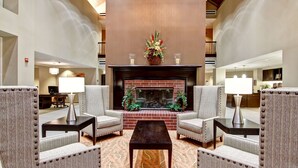 A lobby with a fireplace, two armchairs, a coffee table, and a patterned rug. - Homewood Suites by Hilton Houston-Kingwood Parc-Airport Area (Kingwood)