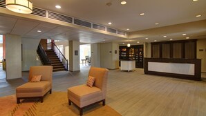 A spacious lobby with two armchairs, a reception desk, and a staircase. - Homewood Suites by Hilton Houston-Kingwood Parc-Airport Area (Kingwood)