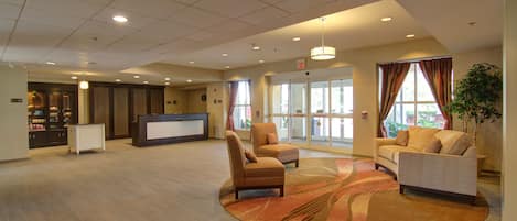 A spacious lobby with a reception desk, seating area, and large windows.