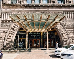 La entrada de un edificio histórico con una cubierta de vidrio y columnas de piedra, con un letrero del Hyatt Regency.
