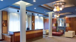 Un vestíbulo de hotel con mostrador de recepción, zona de estar y chimenea.