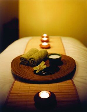 A spa setting with a wooden tray containing rolled towels, a flower, and a bowl of cream. - Hyatt Regency Cleveland At The Arcade (Cleveland)