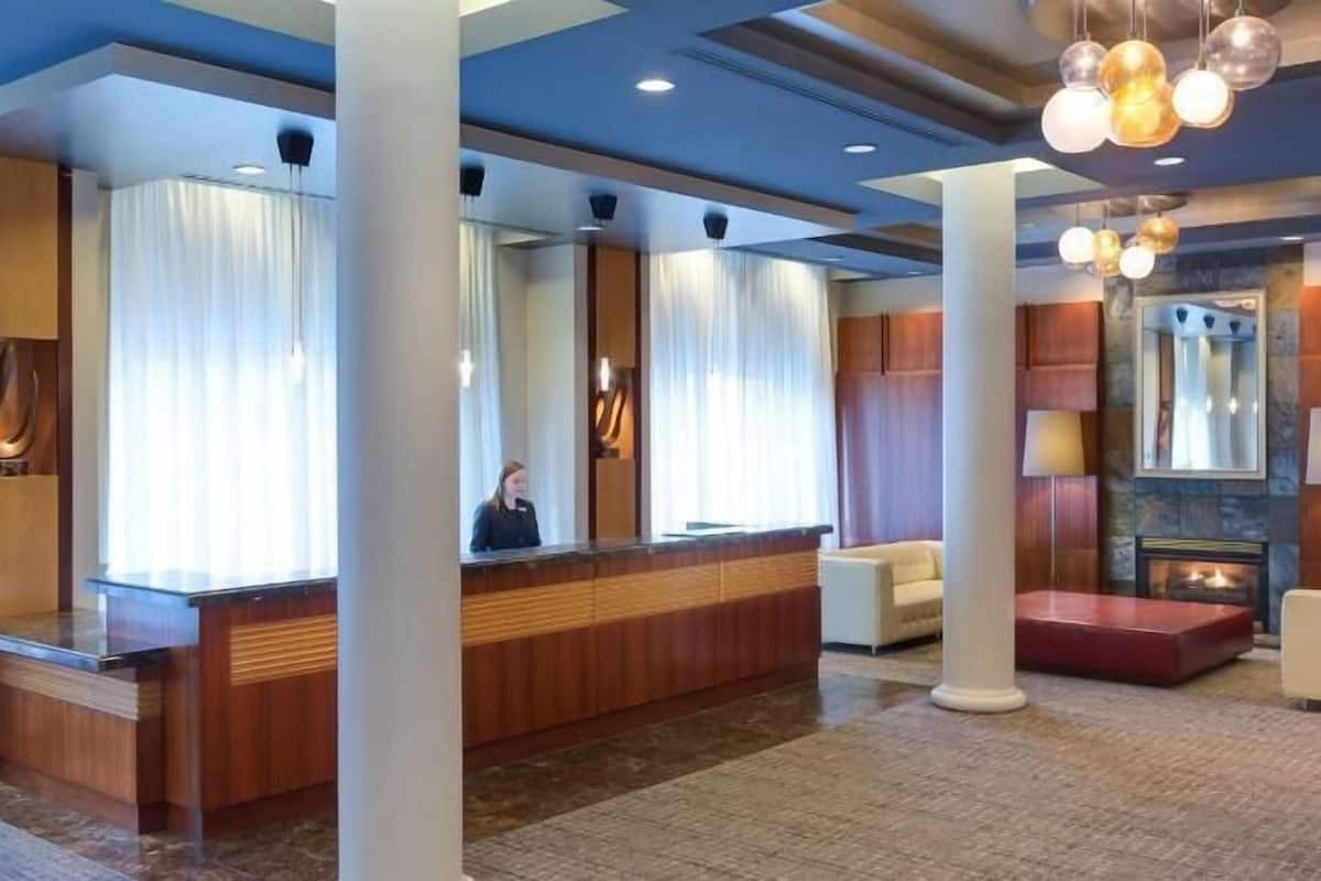 Un vestíbulo de hotel con mostrador de recepción, zona de estar y chimenea.