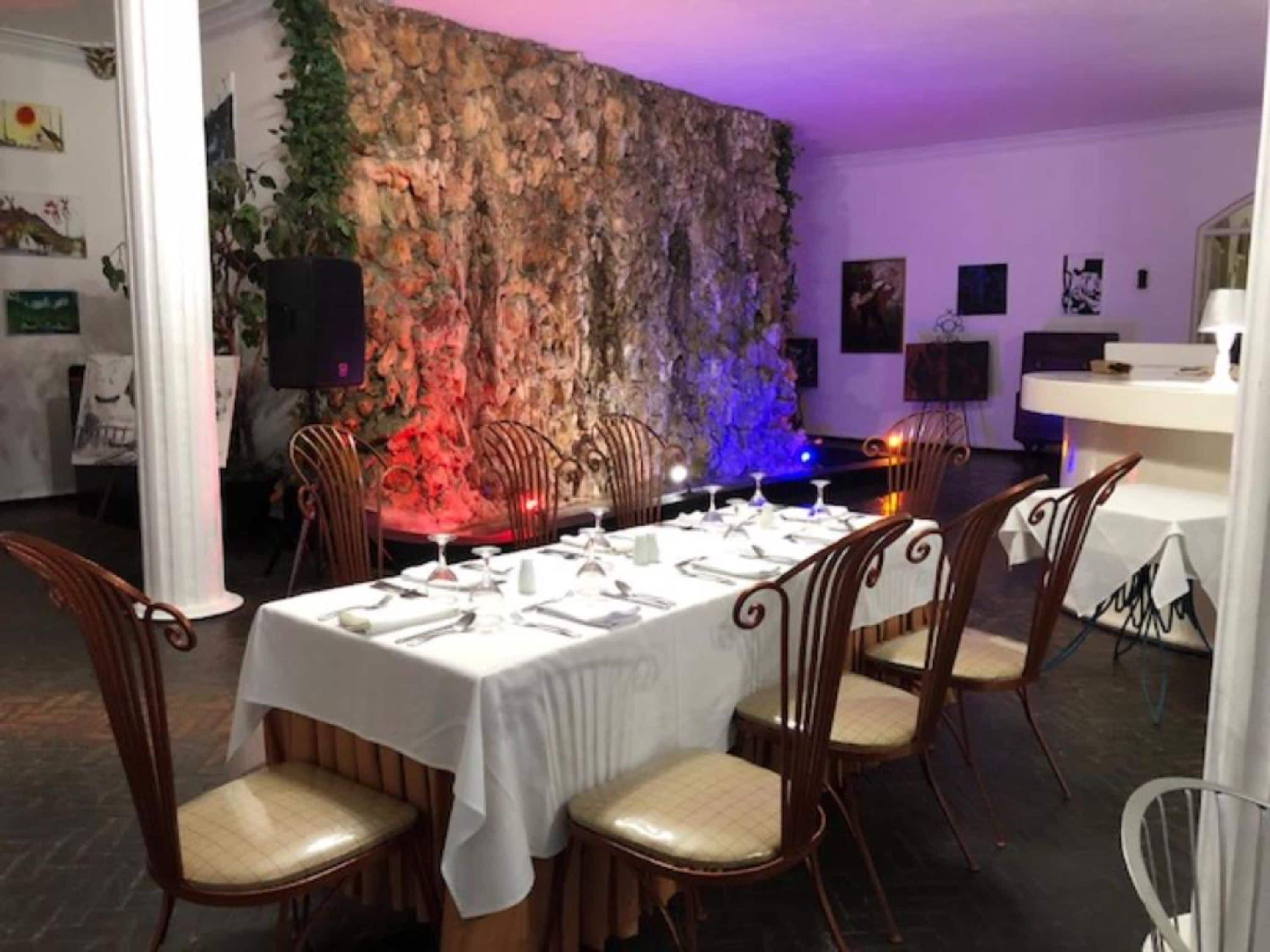 A dining area with a long table set for a meal, surrounded by wooden chairs with cushioned seats.