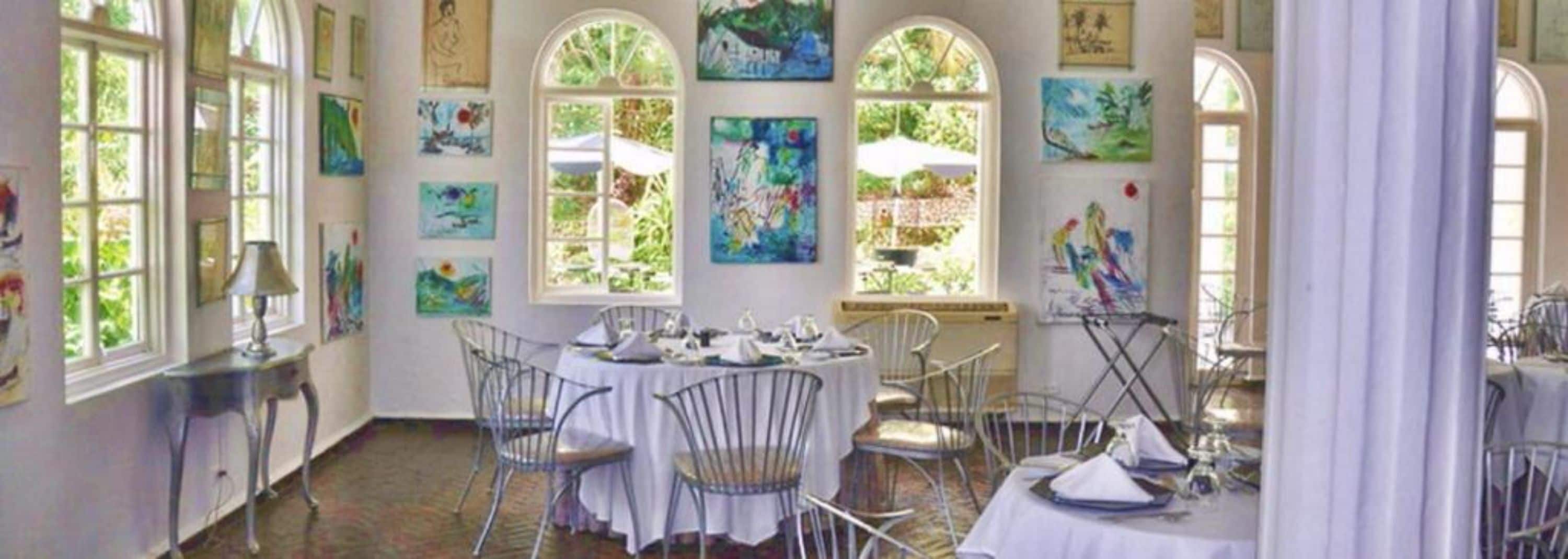 A dining room with a round table, white chairs, and artwork on the walls.