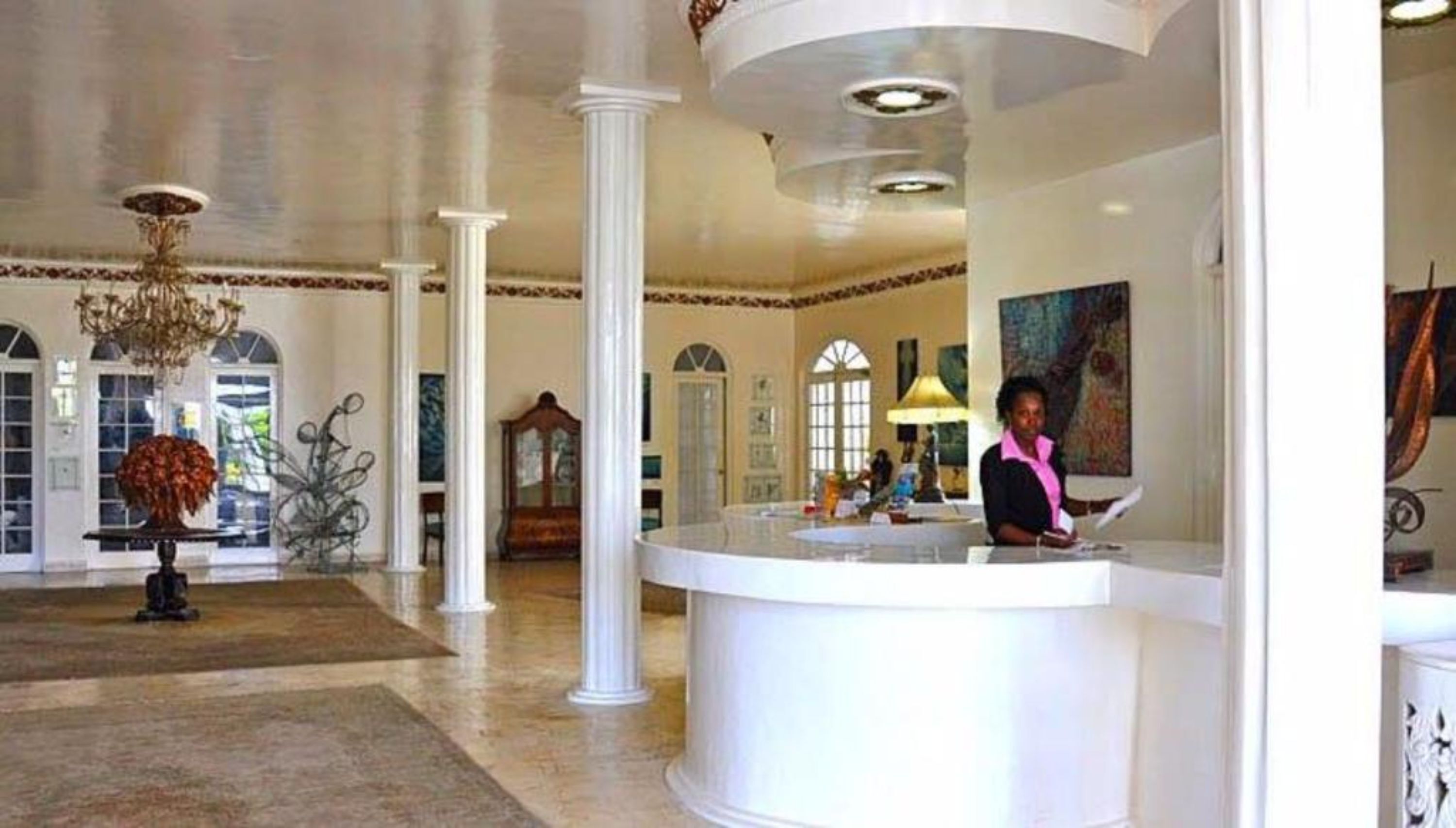 En lobby med reception, søjler, en lysekrone og kunst på væggene.
